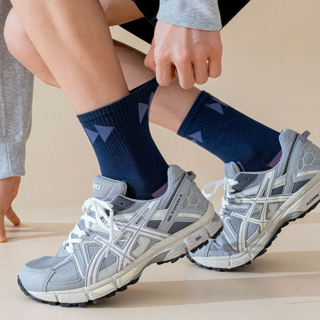 Person wearing navy socks and gray sneakers on a neutral background