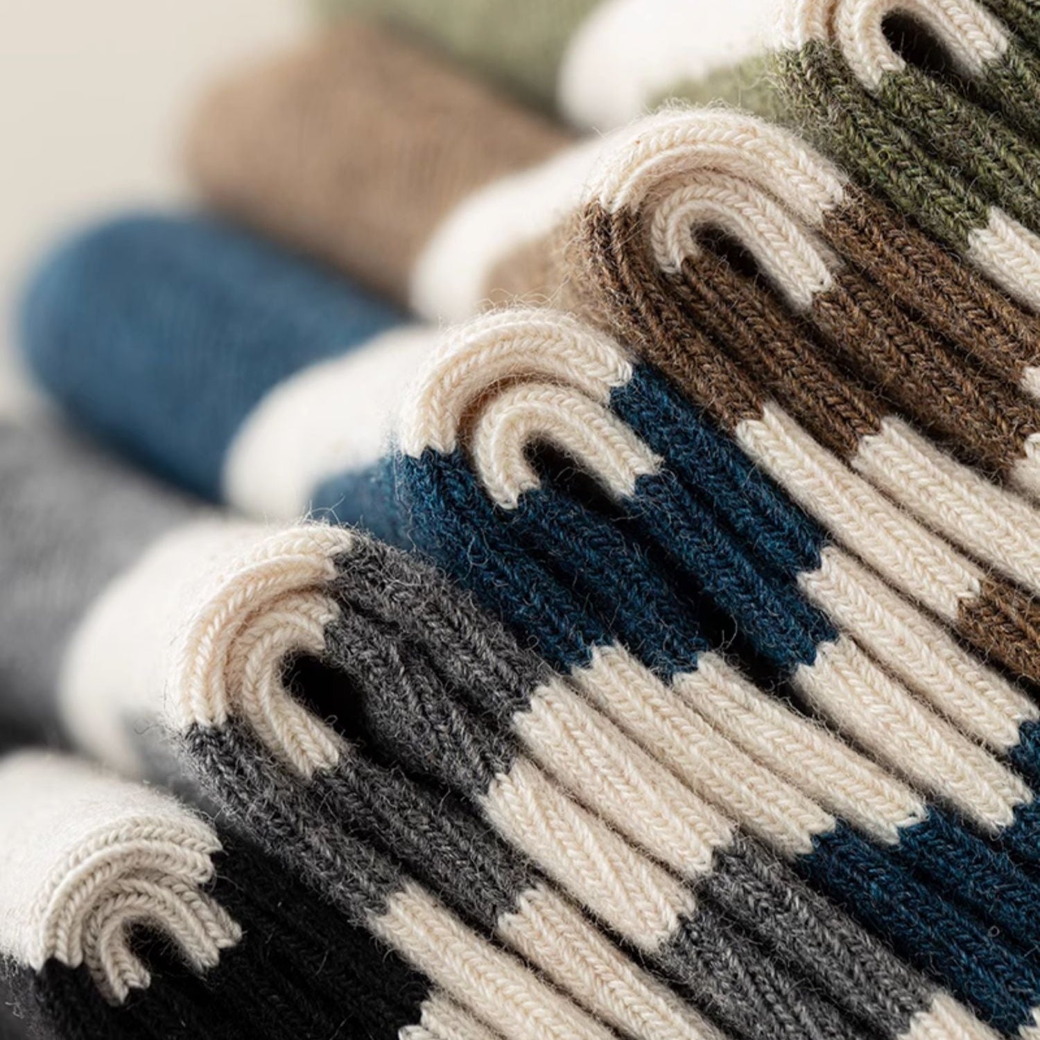 A close-up of folded striped knit socks or sweaters in multiple colors, including navy, blue, brown, beige, gray, and orange