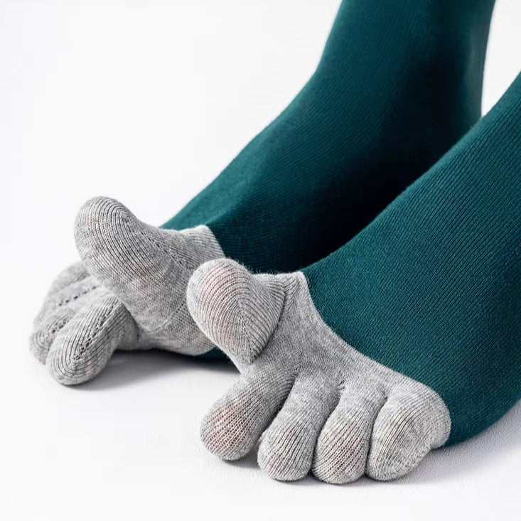 A pair of gray five-toe socks worn on feet, paired with dark teal tights, shown against a clean white background.