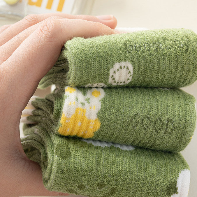 Three folded green knit socks stacked in a hand