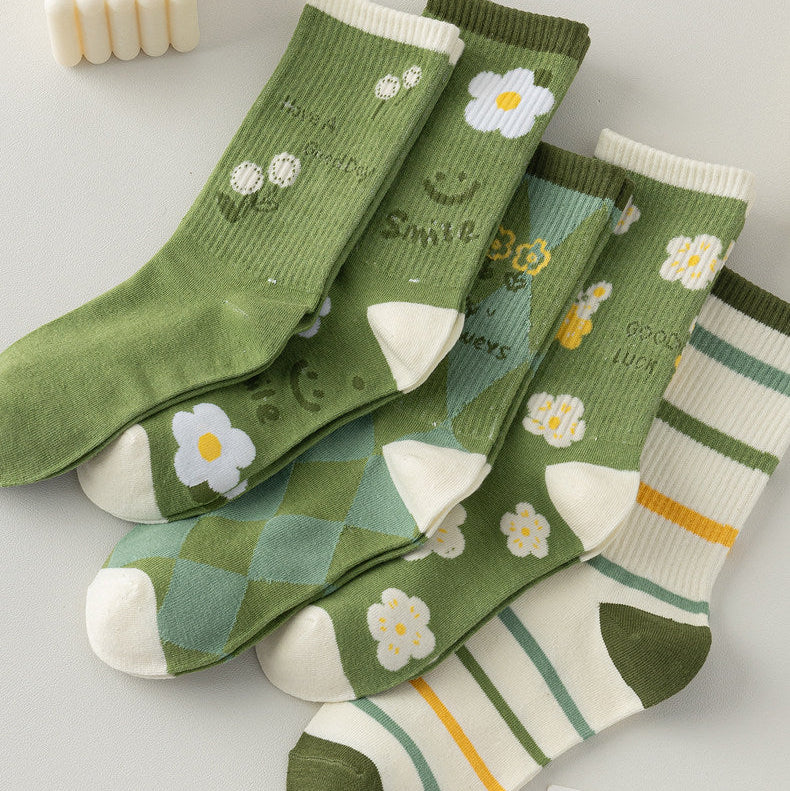 Four pairs of green and white patterned socks arranged on a light gray background 