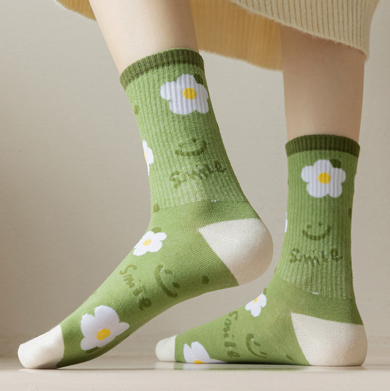 A person wearing light green crew socks with white daisy and smiley face patterns