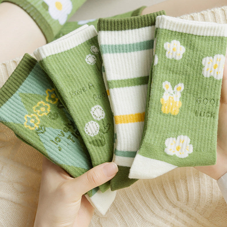 A person holds four pairs of green patterned socks