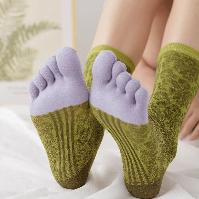 Green and purple five-finger socks worn by a person on a light background