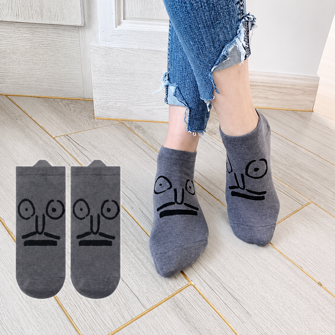 Person wearing gray socks with face designs on a tiled floor.