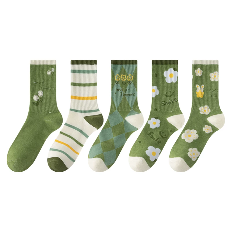 Five pairs of green patterned crew socks displayed side by side on a plain white background. The socks feature various designs including floral prints, stripes, argyle, and bunnies.
