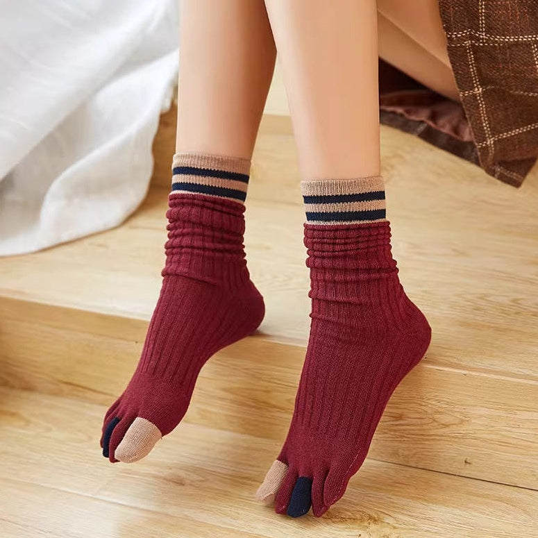 Person wearing red ribbed socks with striped cuffs on a wooden floor.