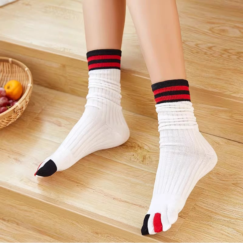 White socks with black and red accents worn on a wooden floor.