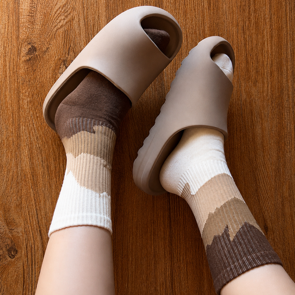 Beige open-toe shoes worn with patterned socks on a wooden floor
