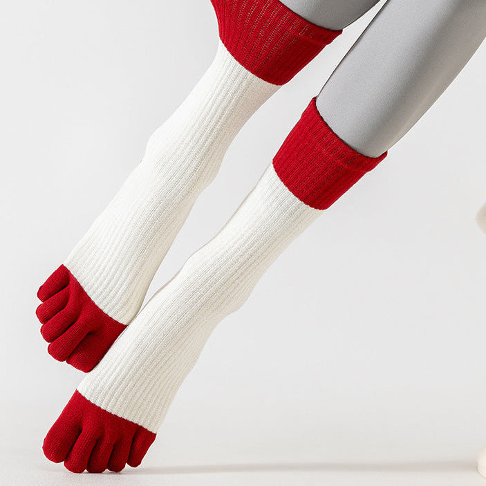Legs wearing white socks with red tips and cuffs on a light gray background.