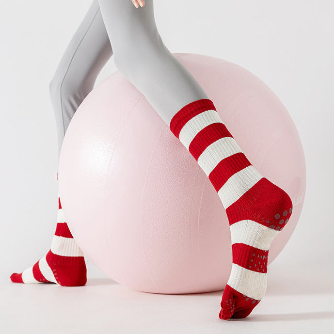 Person wearing gray leggings and red and white striped socks with a pink exercise ball on a light gray background.