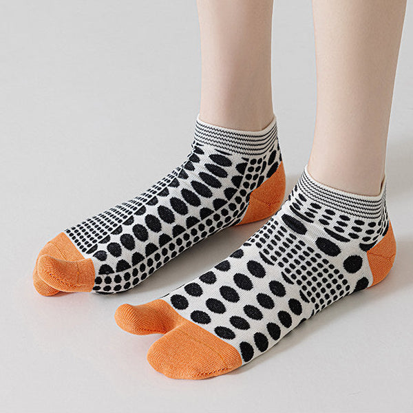Polka dot socks with orange toes and heels on a neutral background