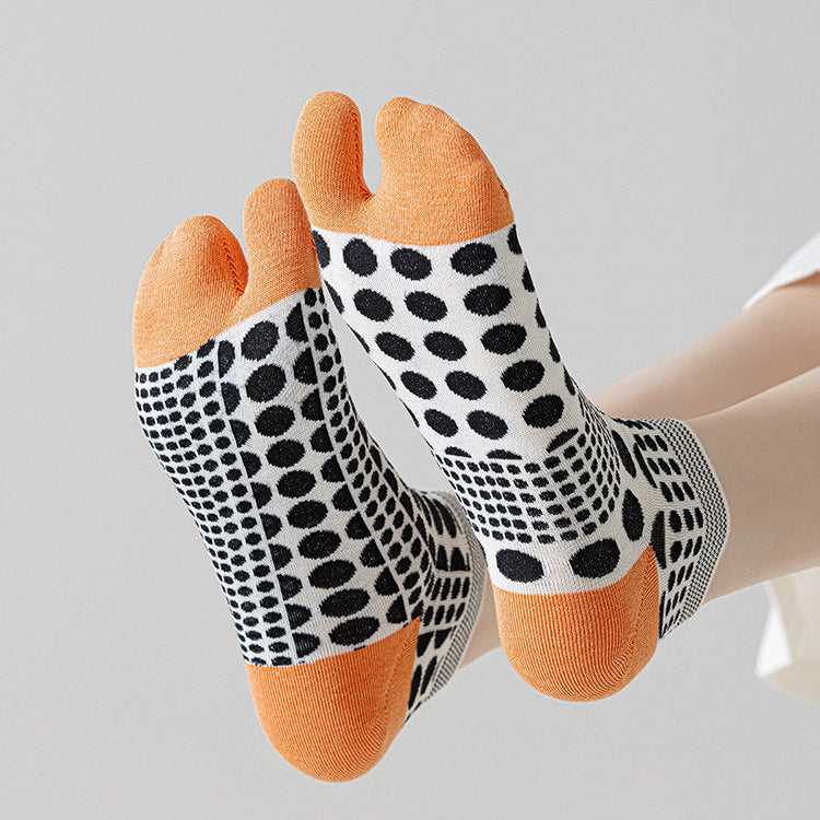 Pair of polka dot socks with orange toes and heels on a light gray background
