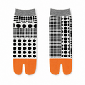 Two pairs of socks with black and white patterned tops and orange toes on a white background