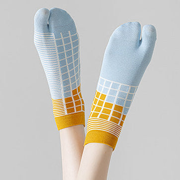 Stack of patterned socks held by a hand and a person wearing colorful tabi socks on a light gray background.