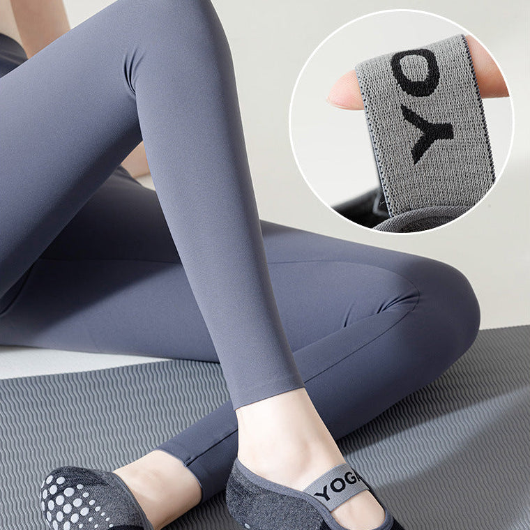 Person wearing gray leggings and black socks with a close-up of the sock brand on a light gray background.